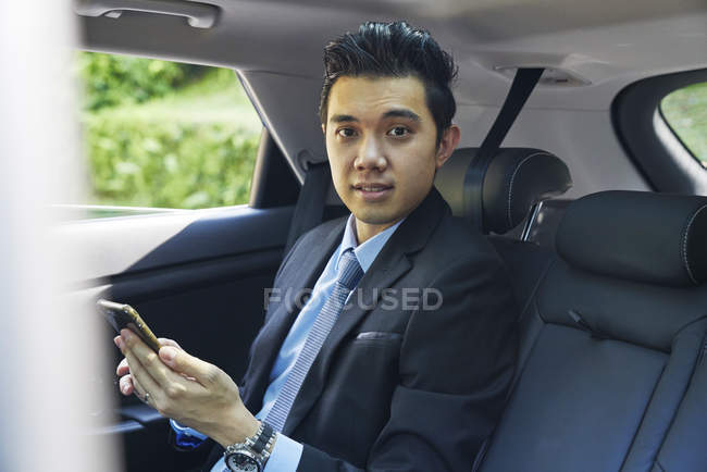 Молодий чоловік бізнесмен перевіряє свій мобільний телефон в машині — стокове фото