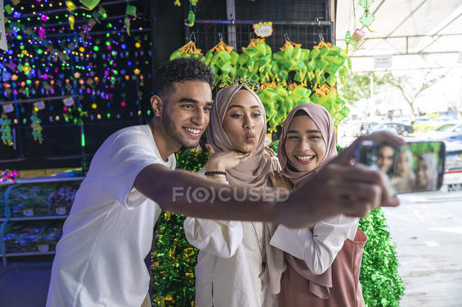 Un grupo de amigos tomando una selfie contra las decoraciones hari raya
. - foto de stock