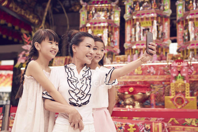 Feliz asiático familia tomando selfie juntos en tradicional singapurense santuario - foto de stock