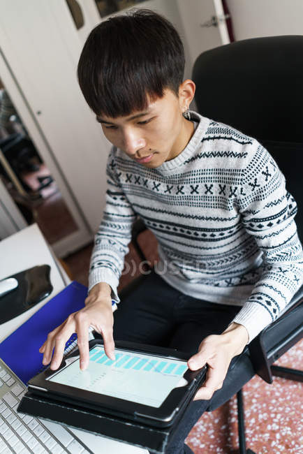 Jeune homme asiatique adulte en utilisant une tablette numérique à la maison — Photo de stock