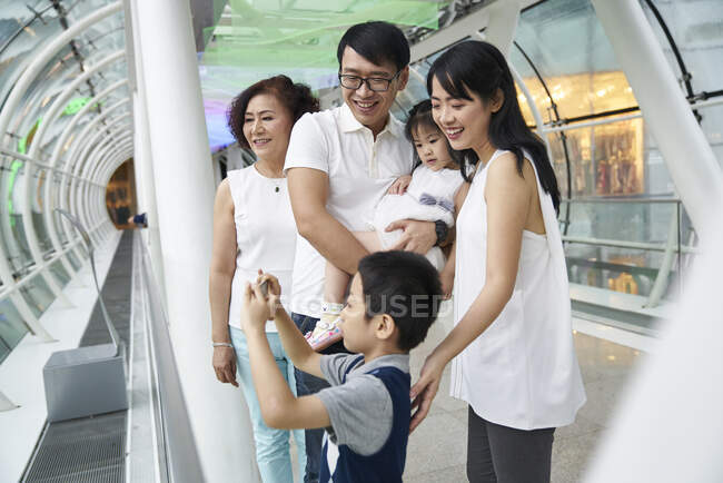 COMMUNIQUÉS Happy young asian family together, boy taking photo — Photo de stock