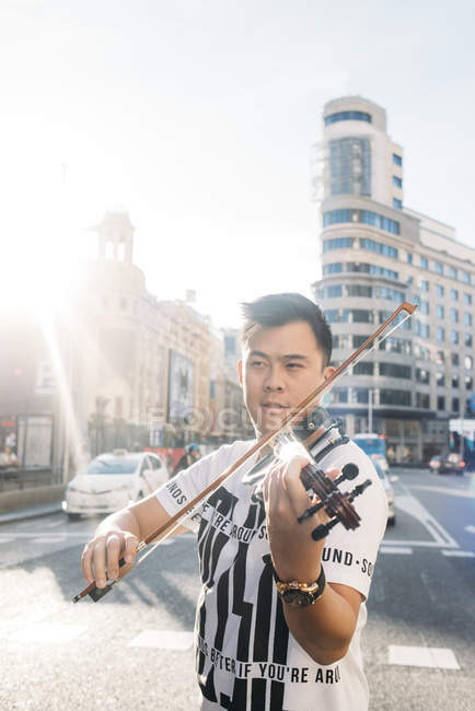 Молодой азиатский музыкант мужчина со скрипкой в городе — стоковое фото