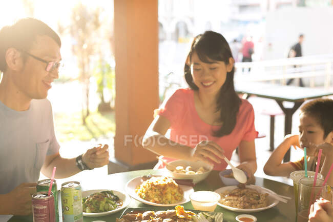 LIBERTAS Familia asiática feliz comiendo juntos en la cafetería - foto de stock