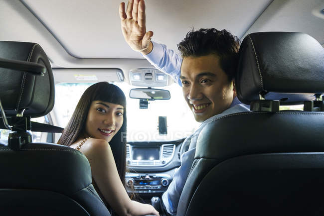 Joven conductor masculino dando a su pasajero femenino un High-five - foto de stock