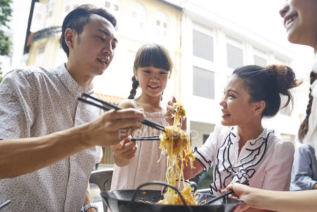 Feliz asiático familia comer fideos juntos en calle café - foto de stock