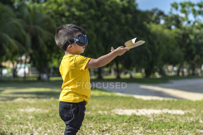Un niño jugando con un avión de juguete. - foto de stock