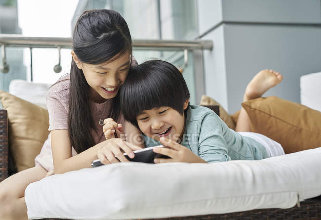 Feliz joven asiático familia juntos, niños usando digital tablet en casa - foto de stock