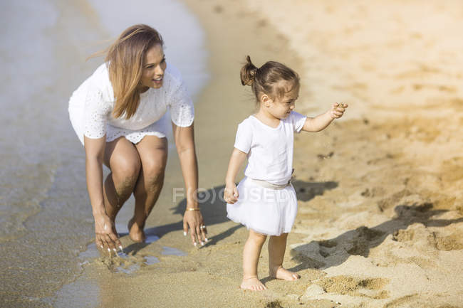 Feliz joven madre e hija pasar tiempo juntos en la playa - foto de stock
