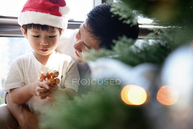 Happy asian family celebrating Christmas together at home, father and son decorating fir tree — Stock Photo