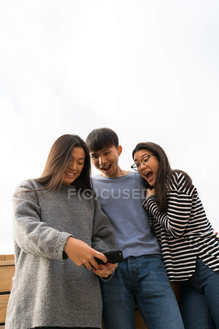 Jóvenes asiáticos juntos usando smartphone en blacony - foto de stock