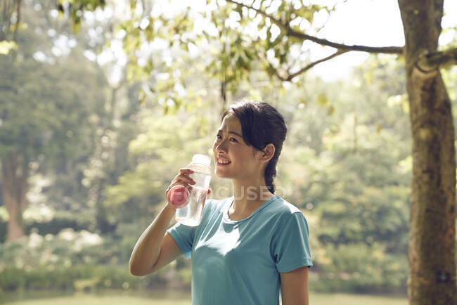Mujer hidratante después de hacer ejercicio en Botanic Gardens, Singapur - foto de stock