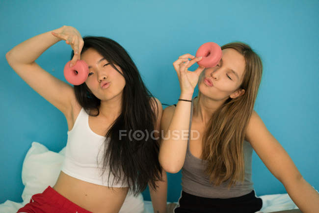 Deux jeunes femmes s'amusent avec des beignets — Photo de stock