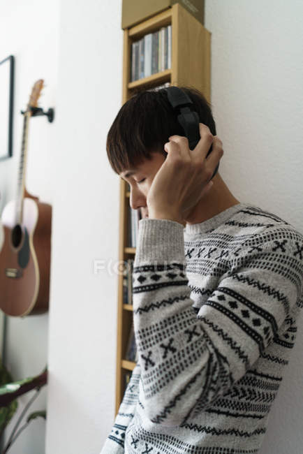 Jovem adulto asiático homem usando fones de ouvido em casa — Fotografia de Stock