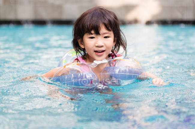 Bambina che nuota in piscina con carri allegorici . — Foto stock