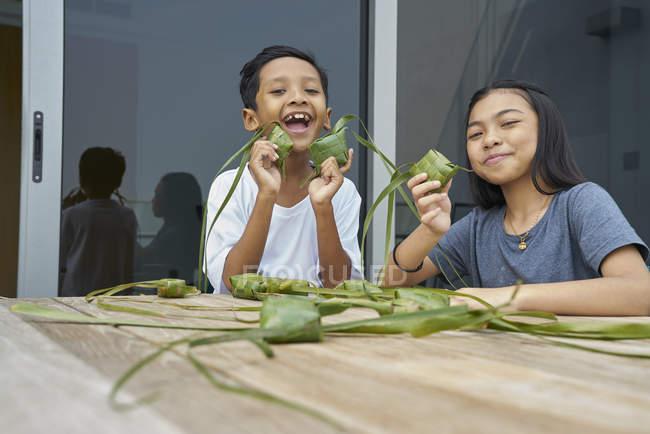 Jóvenes asiáticos hermanos celebrando hari raya juntos en casa y hacer decoraciones - foto de stock