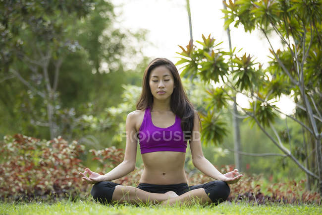 Uma jovem mulher asiática está fazendo ioga no parque em Marina Bay . — Fotografia de Stock