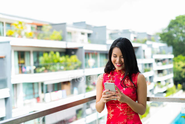 Glückliche asiatische Frau mit Smartphone auf Balkon — Stockfoto