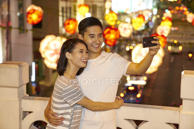 Joven asiático pareja pasando tiempo juntos en tradicional bazar en chino nuevo año y tomando selfie - foto de stock