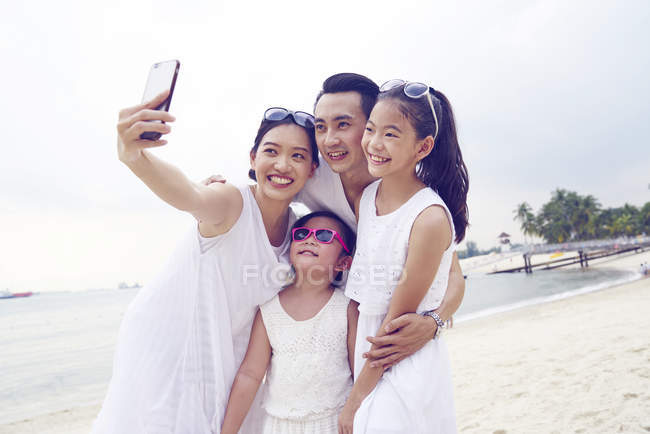 Heureux asiatique famille passer du temps ensemble sur plage et prendre selfie — Photo de stock