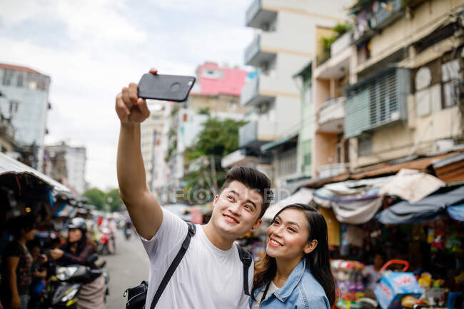 COMMUNIQUÉS Jeune couple asiatique prenant selfie dans un marché local à Ho Chi Minh Ville, Vietnam — Photo de stock