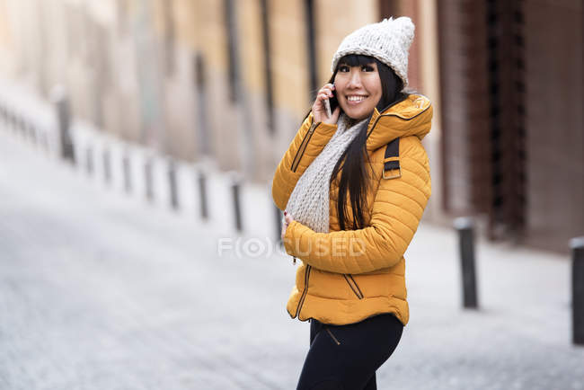 Молода приваблива азіатська жінка використовує смартфон на вулиці — стокове фото