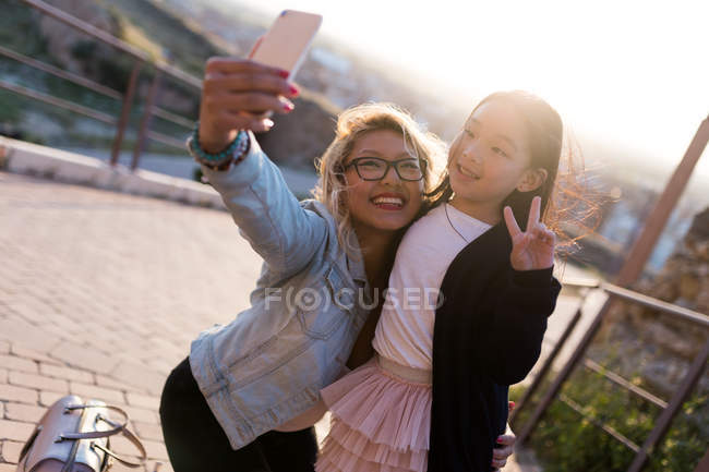 Glückliche junge Mutter mit ihrer Tochter, die an einem sonnigen Tag ein Selfie in der Stadt macht. — Stockfoto