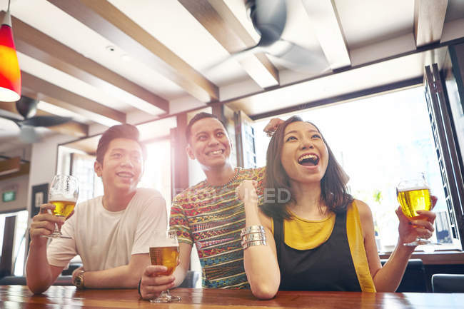 Feliz joven asiático amigos juntos en bar con cerveza - foto de stock