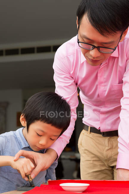 Батько вчить каліграфії сина китайського Нового року. — стокове фото