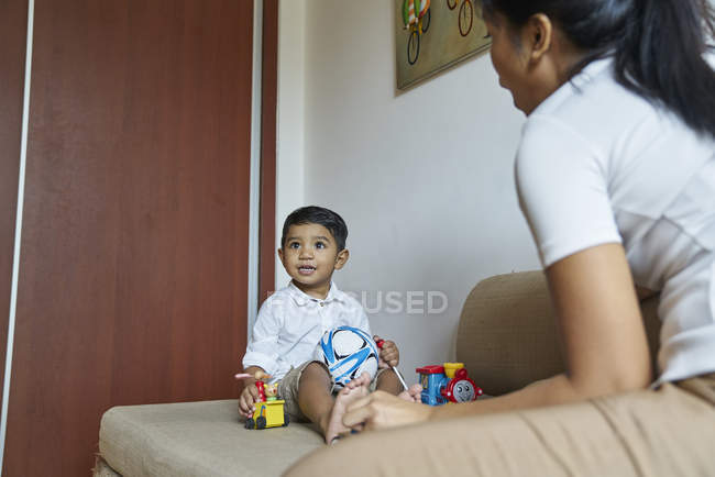 Asiatico madre e figlio bonding oltre giocattoli su il divano — Foto stock