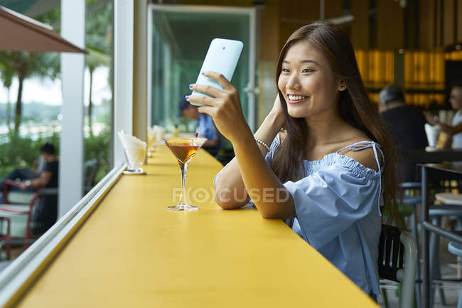 Atraente jovem asiático mulher usando smartphone no café — Fotografia de Stock