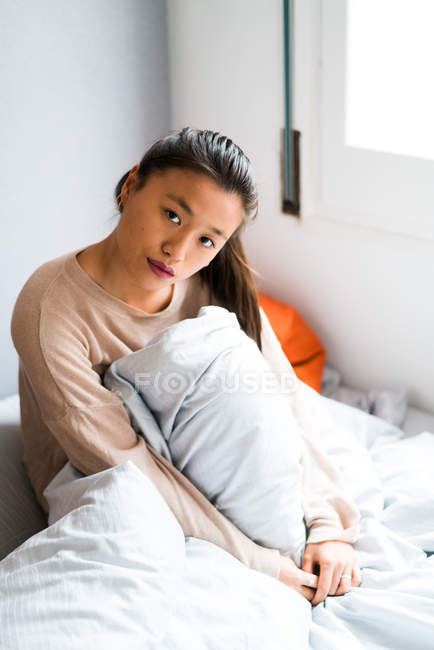 Молода доросла жінка на ліжку дивиться на камеру — стокове фото