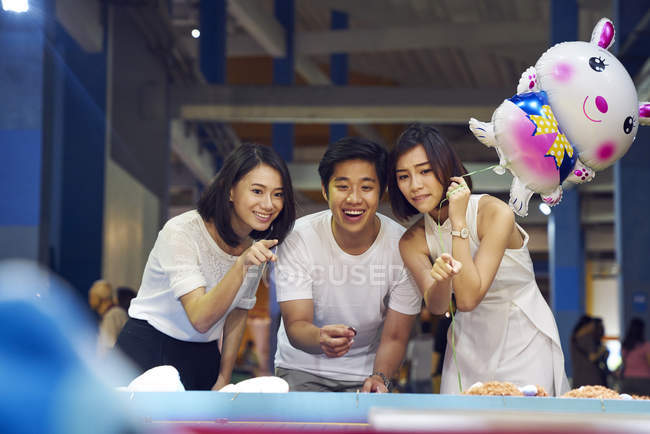 Friends tossing a coin at a carnival to win prizes in Singapore — Stock Photo