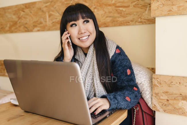 Joven atractivo asiático mujer usando smartphone en café - foto de stock