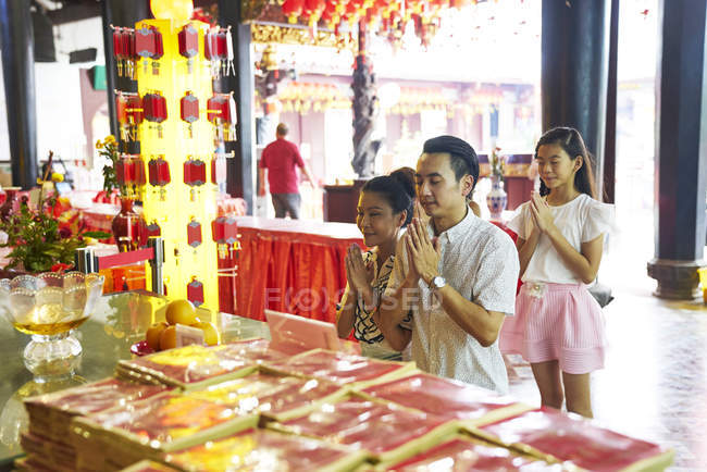 Happy asian family praying together in traditional Singaporean shrine — Stock Photo