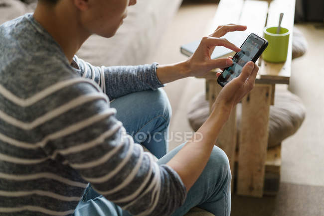 Молодий дорослий азіатський чоловік використовує смартфон вдома — стокове фото