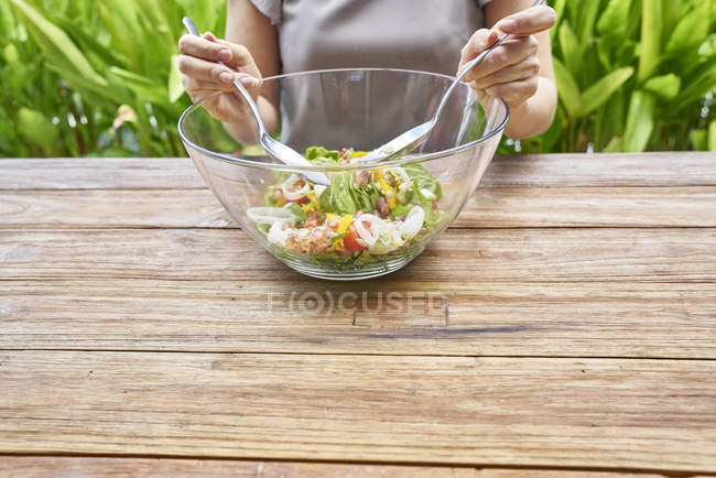 Imagen recortada de la mujer ensalada de cocina en la cocina - foto de stock