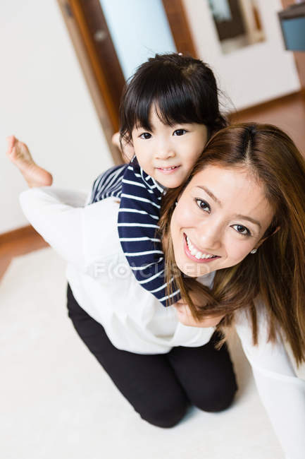 Filha abraçando a mãe por trás em casa — Fotografia de Stock