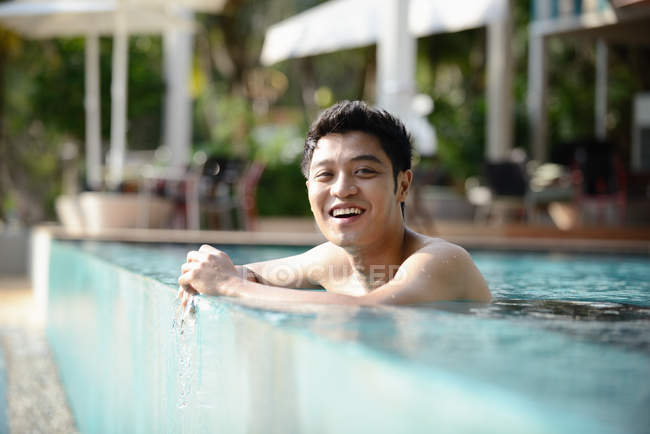 Молодой привлекательный азиатский мужчина расслабляется в бассейне — стоковое фото