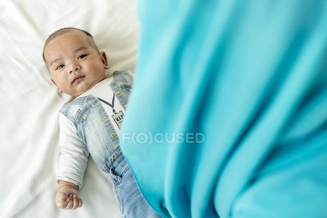 Baby lying down on the bed looking at the camera. — Stock Photo