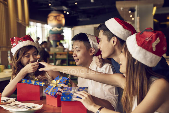 Felici giovani amici asiatici che celebrano il Natale insieme nel caffè e condividono regali — Foto stock