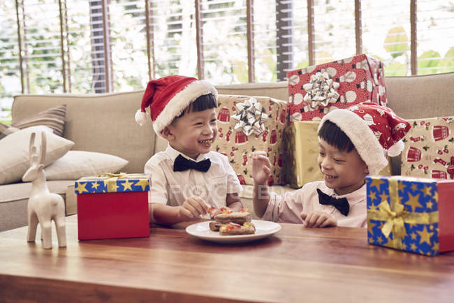 Щаслива азіатська сім'я святкує Різдво разом, два хлопчики з різдвяним печивом — стокове фото