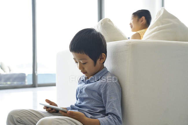 Two cute brother and sister at home, brother using tablet — Stock Photo