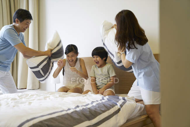 Щаслива молода азіатська сім'я разом подушка бореться вдома — стокове фото
