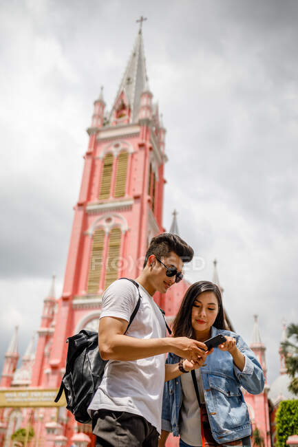 COMMUNIQUÉS Jeune couple vietnamien utilisant un smartphone devant l'église Tan Dinh, Saigon. — Photo de stock