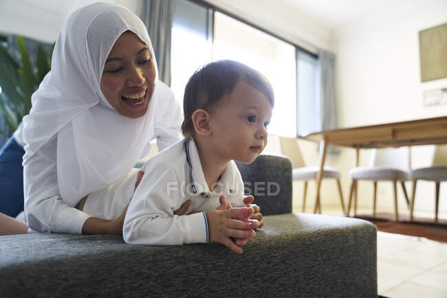 Mãe em Hijab brincando com seu filho na sala de estar — Fotografia de Stock
