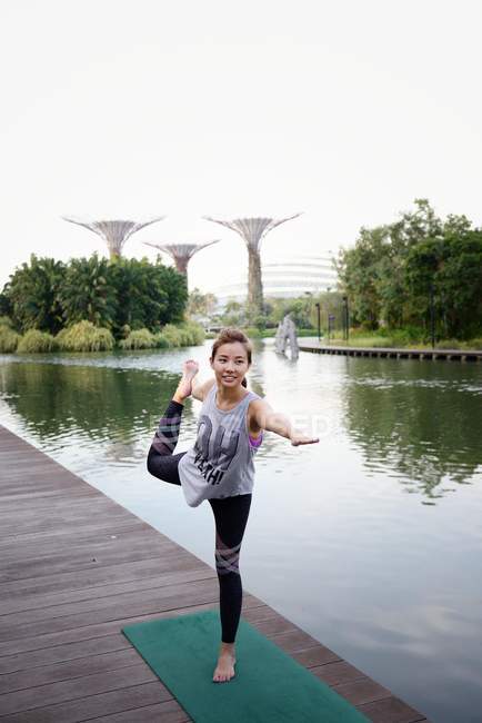 Jovem asiático mulher desportiva fazendo alongamento perto do lago — Fotografia de Stock