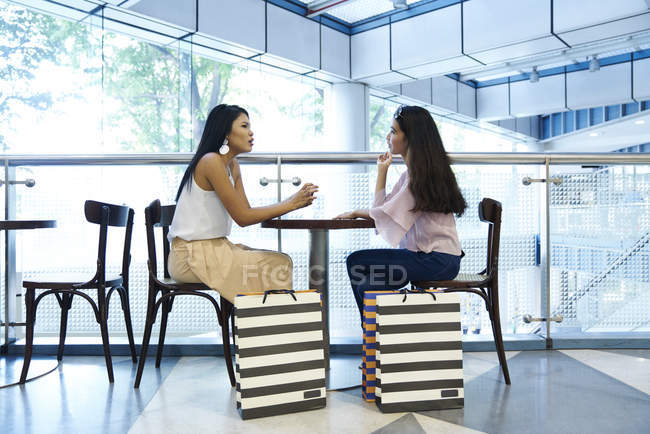 Two beautiful Malay resting at a cafe after shopping — Stock Photo