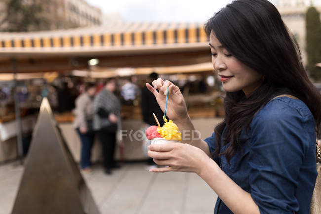 Chinesische Frau mit langen Haaren isst Eis auf den Straßen von Barcelona, Spanien — Stockfoto
