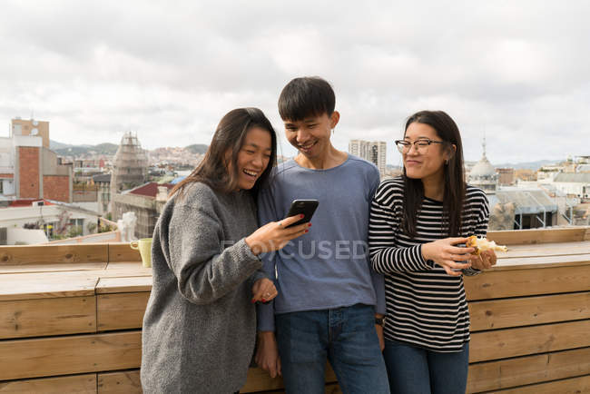 Jovens asiáticos pessoas juntos usando smartphone na varanda — Fotografia de Stock