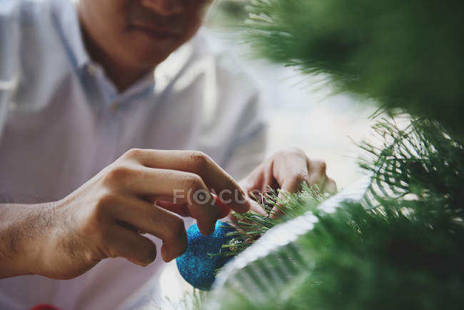 Щасливий молодий азіатський чоловік прикрашає ялинку — стокове фото